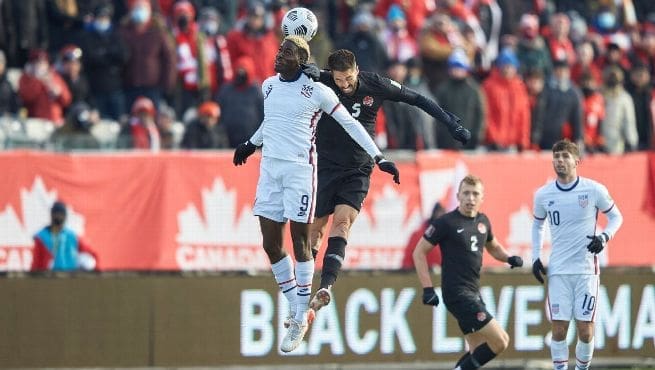 Gyasi Zardes (#9) of USMNT competing for header against Canada player during World Cup qualifier match in Hamilton
