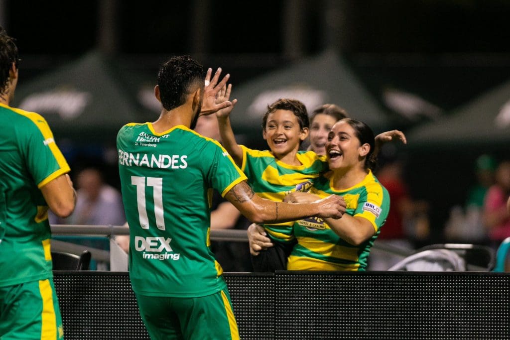 Leo Fernandes celebrates the goal with his wife and son on the sideline. 