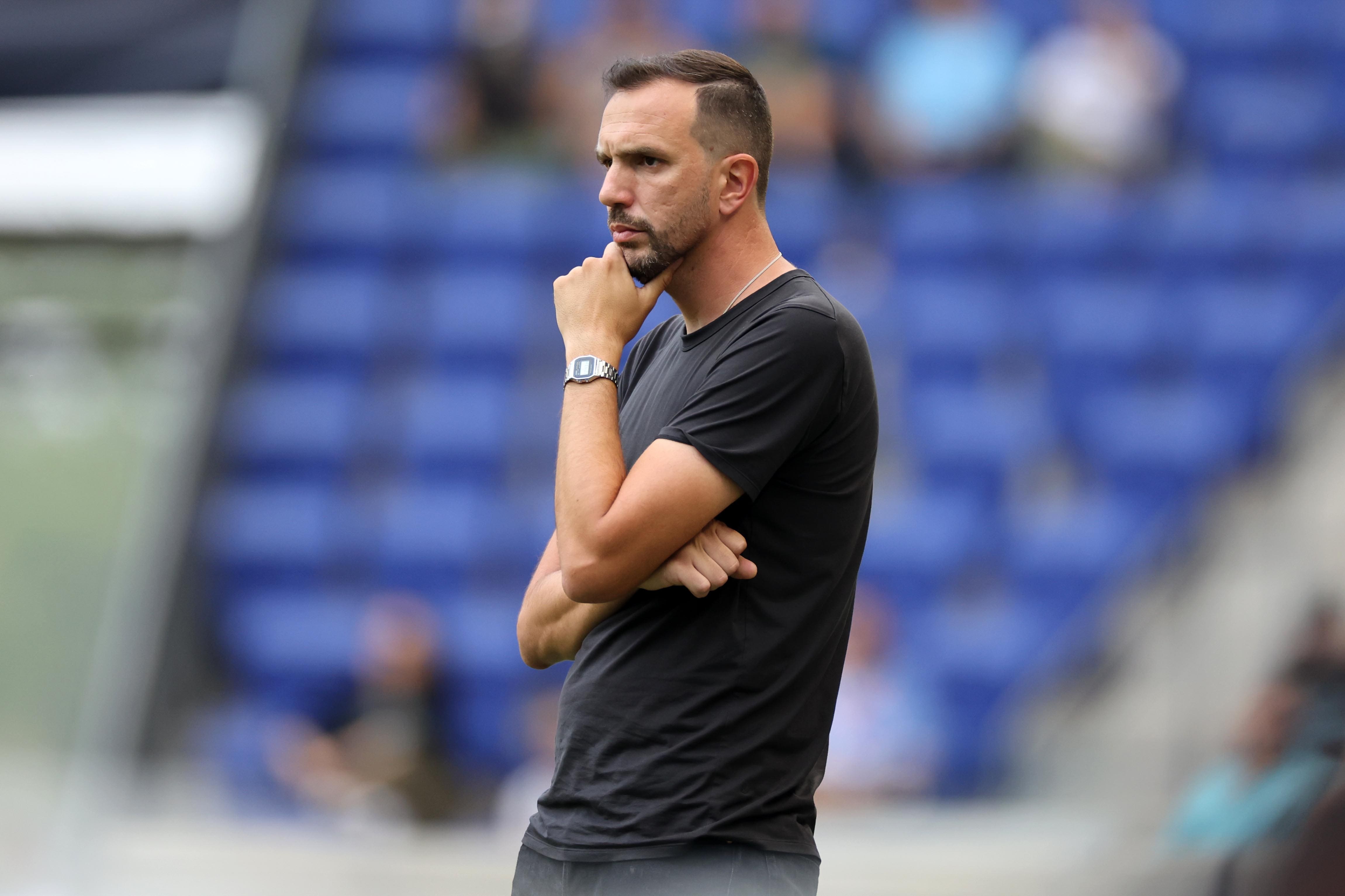 Gotham FC head coach Juan Carlos Amorós stands on the sideline with a thoughtful expression during a match at Red Bull Arena.
