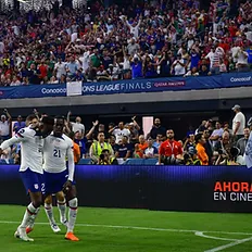 Tim Weah celebrates Folarin Balogun's goal near corner flag during USMNT CONCACAF Nations League final, players in white jerseys and navy shorts