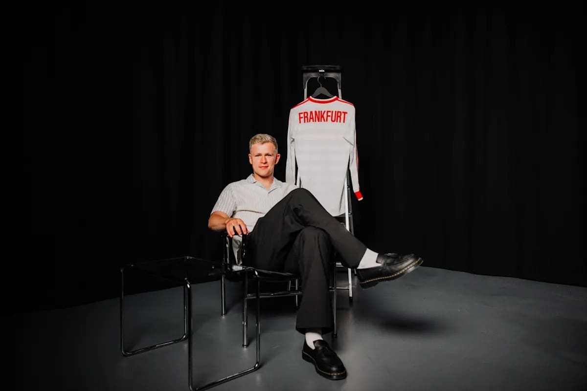 Jonathan Burkardt posing next to a white Eintracht Frankfurt jersey