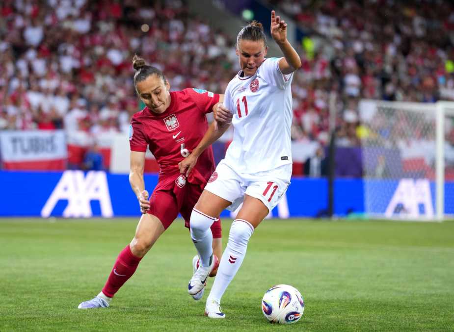 A competitive moment from the 2025 UEFA Women's Euros match between Poland and Denmark, showcasing a Polish player in a red kit challenging a Danish player in white for possession of the ball.
