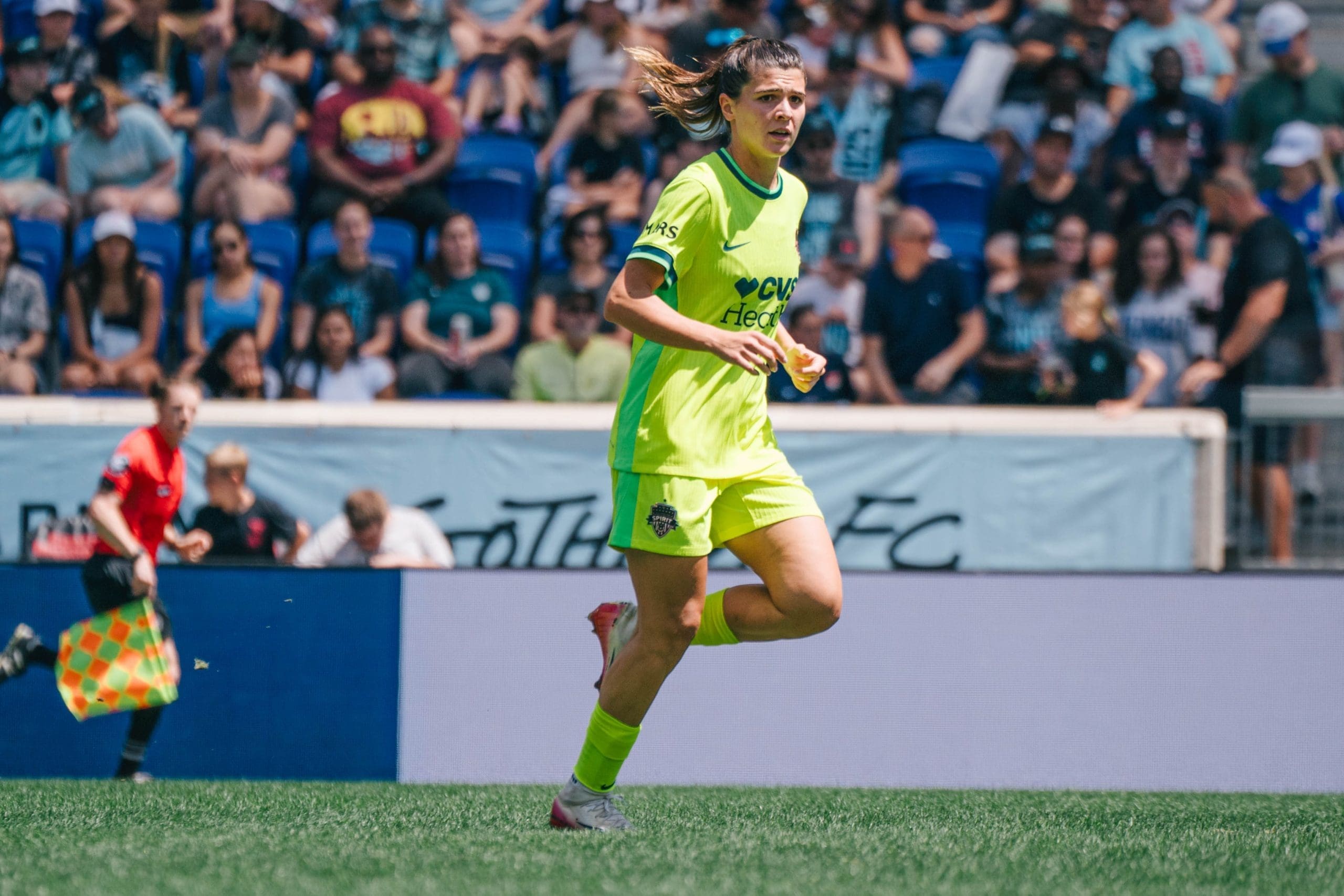 Sofia Cantore runs in bright green Washington Spirit jersey during NWSL match against Gotham FC with crowd in background