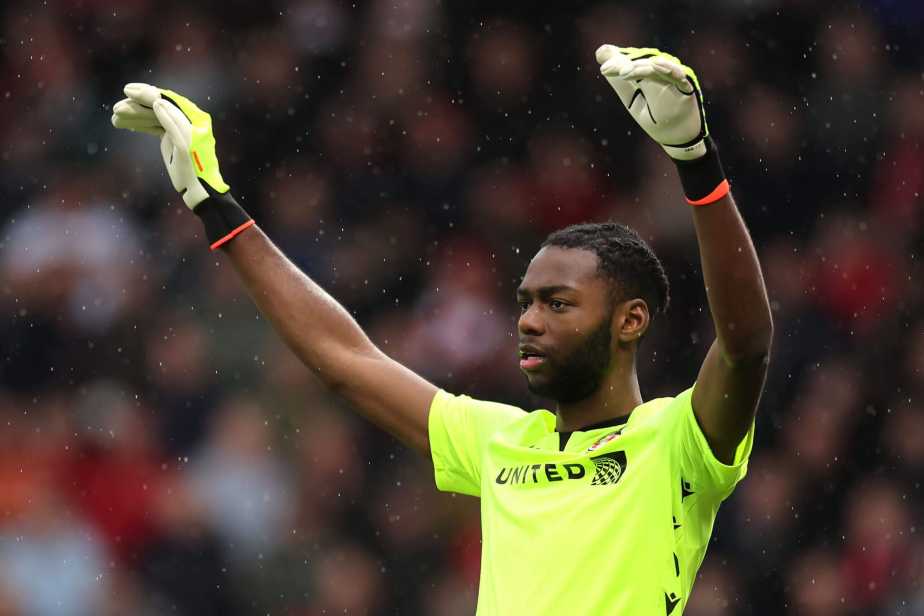Wrexham AFC goalkeeper Michael Okonkwo in action during a match, wearing the team's goalkeeper kit while making a save or positioning for play