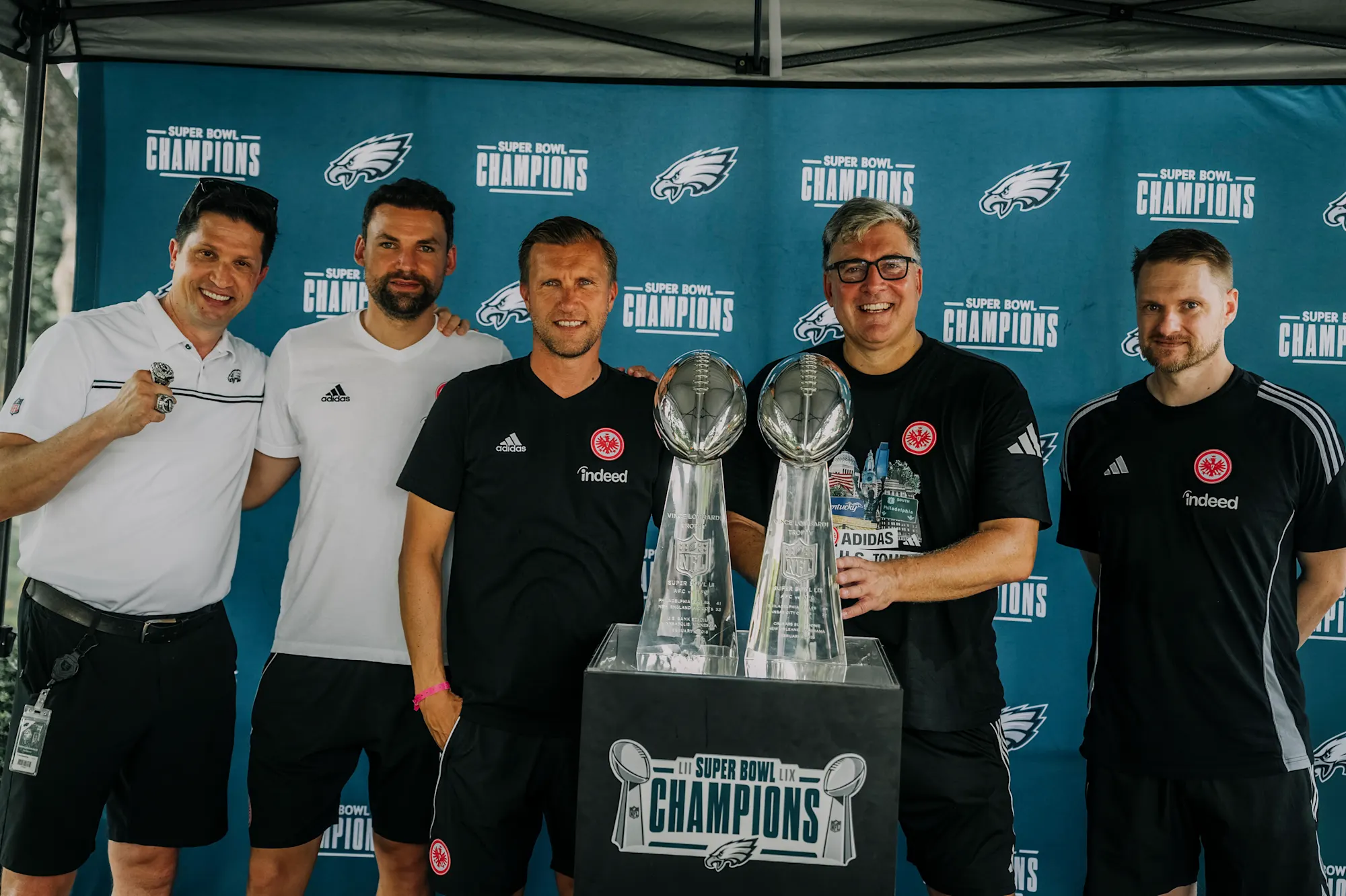 Around the Philadelphia Eagles Super Bowl Trophies (from Left) Norman Vossschulte (Vice President of Fan Experience & Sustainability Philadelphia Eagles), Ole Siegel(Speaker of the sports board), Sports Board Member Markus Krösche, Board Spokesman Axel Hellmann, and Jan Martin Strasheim (Director of Communications & Brand). Credit: Eintracht Frankfurt