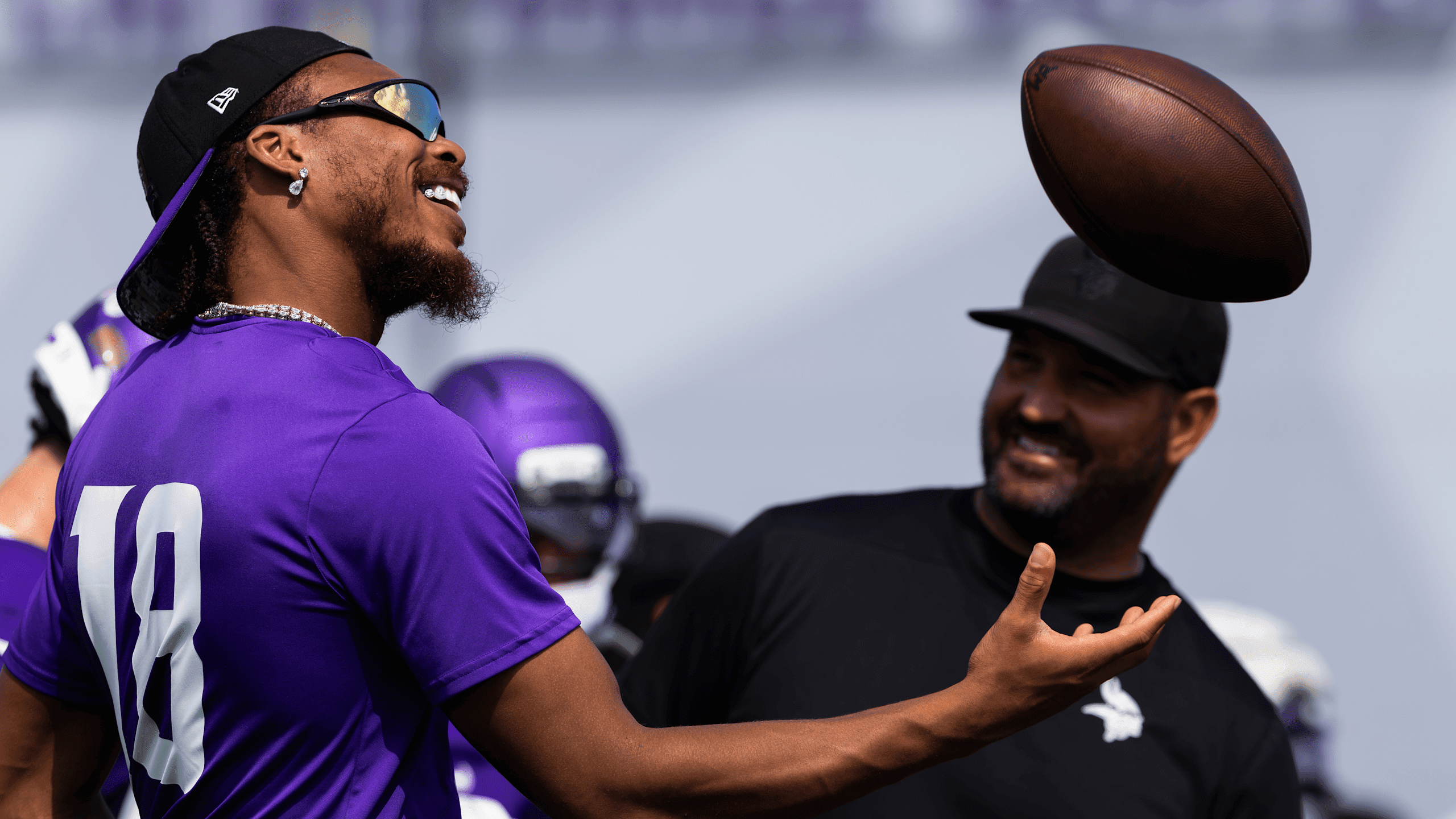 Justin Jefferson smiling and catching football during Minnesota Vikings training camp practice wearing purple jersey number 18