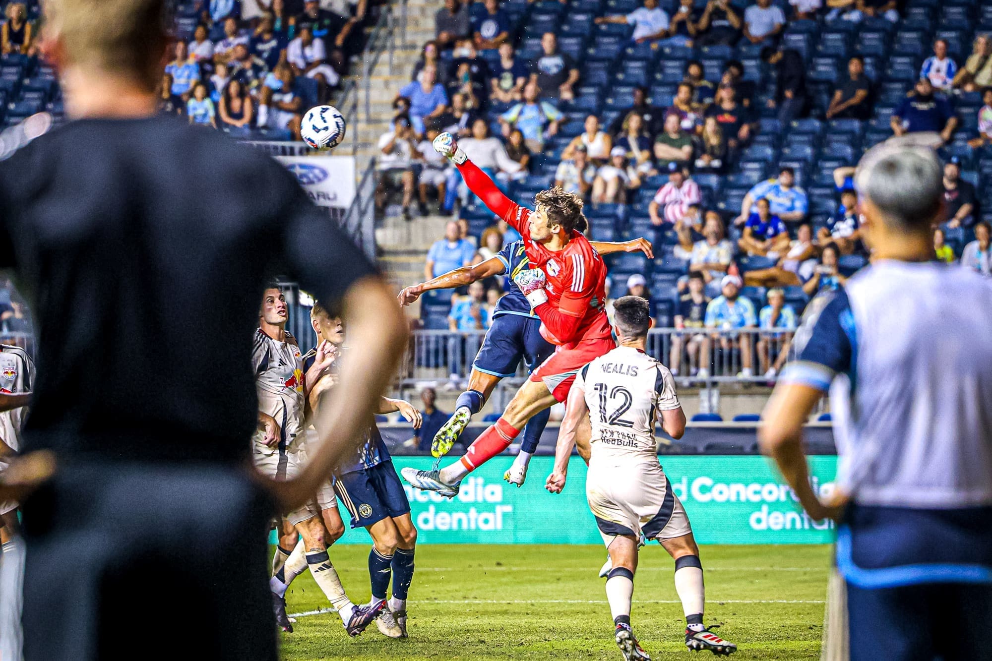 New York Red Bulls goalkeeper AJ Marcucci makes aerial save against Philadelphia Union's Olwethu Makhanya during MLS match at Subaru Park