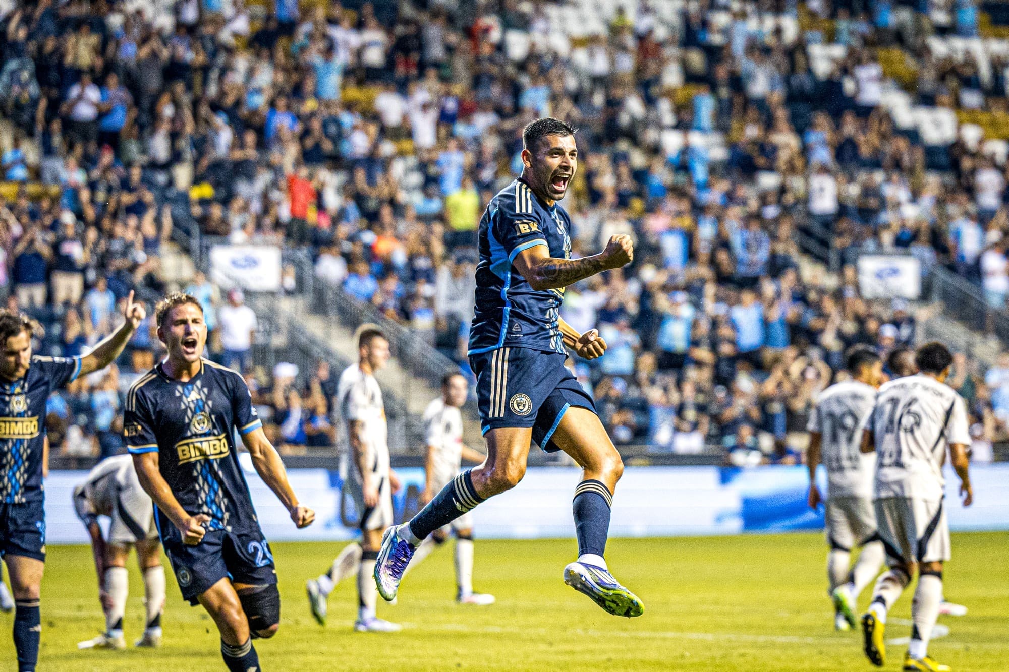 Philadelphia Union player Tai Baribo leaps in celebration after scoring goal while teammate celebrates in background during MLS match