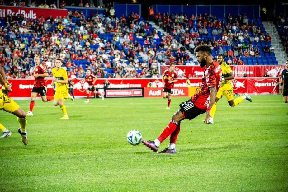 New York Red Bulls forward Eric Maxim Choupo-Moting attempts to play a pass through Columbus Crew defenders during MLS match at Red Bull Arena with crowd in background