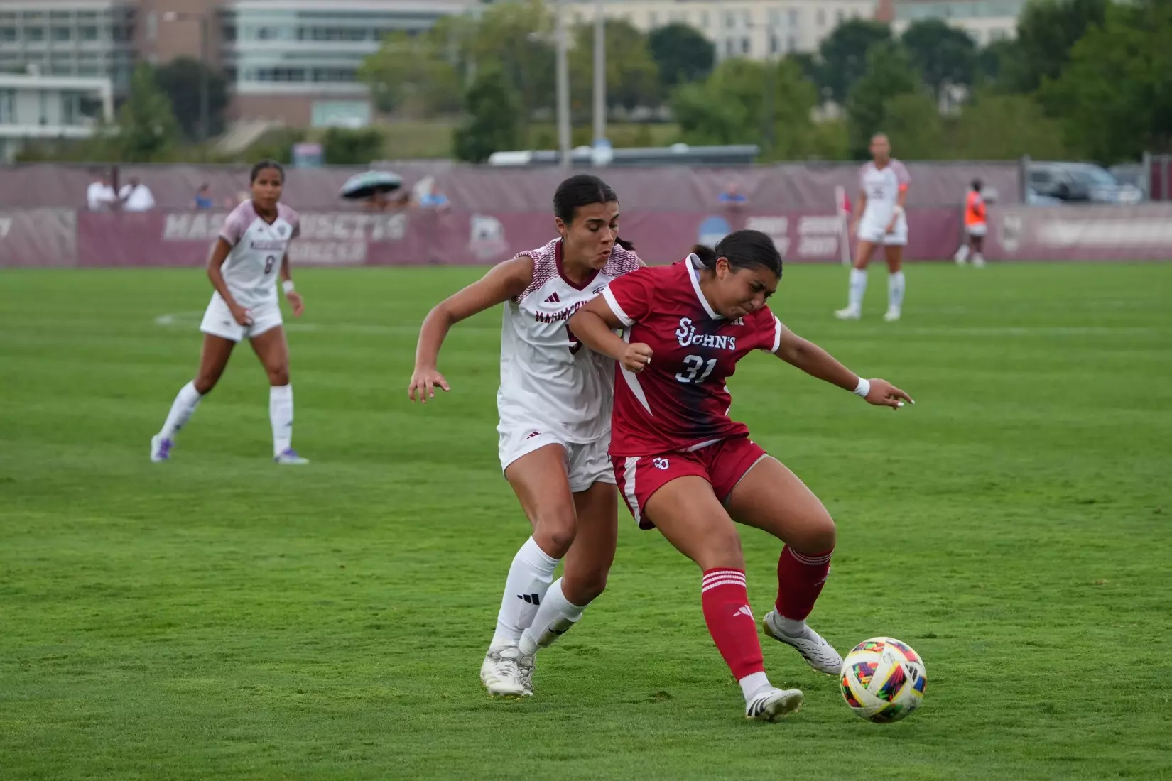 St. John's University women's soccer player Madison Mariani fights to maintain possession of the ball while being challenged by an opposing defender during a match