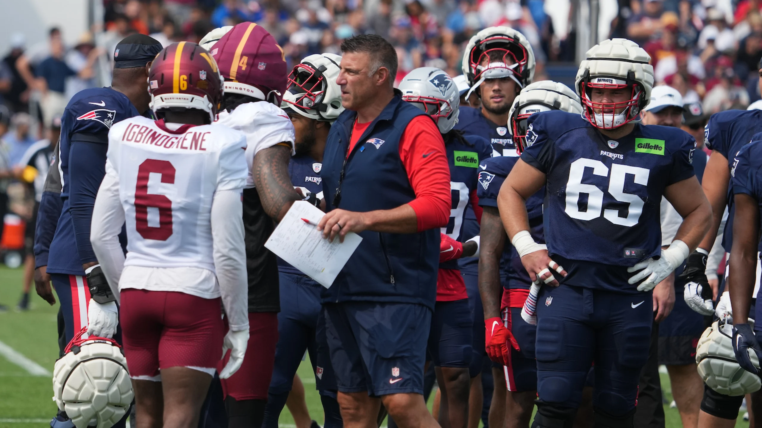 New England Patriots head coach Mike Vrabel in middle of scrum between New England Patriots and Washington Commanders players on sideline.