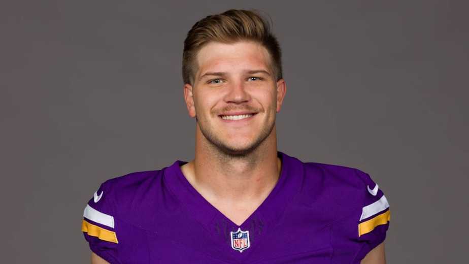 Portrait of a young man wearing a Minnesota Vikings football jersey, smiling at the camera.