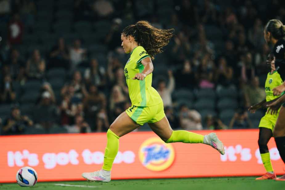 Trinity Rodman #2 of Washington Spirit in bright yellow away kit dribbles with the ball during match against Angel City FC at BMO Stadium, with stadium crowd in background