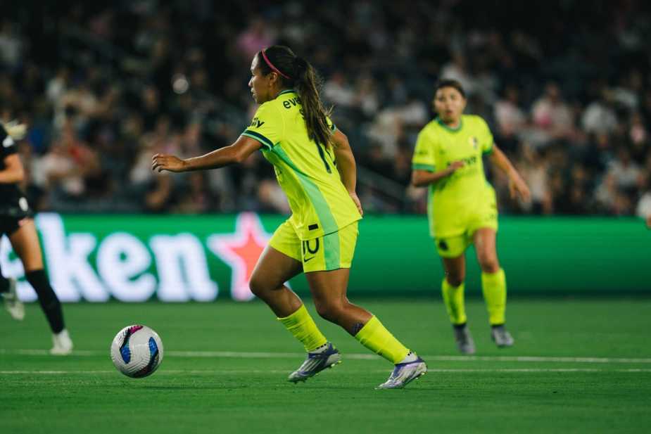 Leicy Santos #10 of Washington Spirit in the yellow away kit controls the ball during buildup play, with Heineken advertising boards visible in the background at BMO Stadium