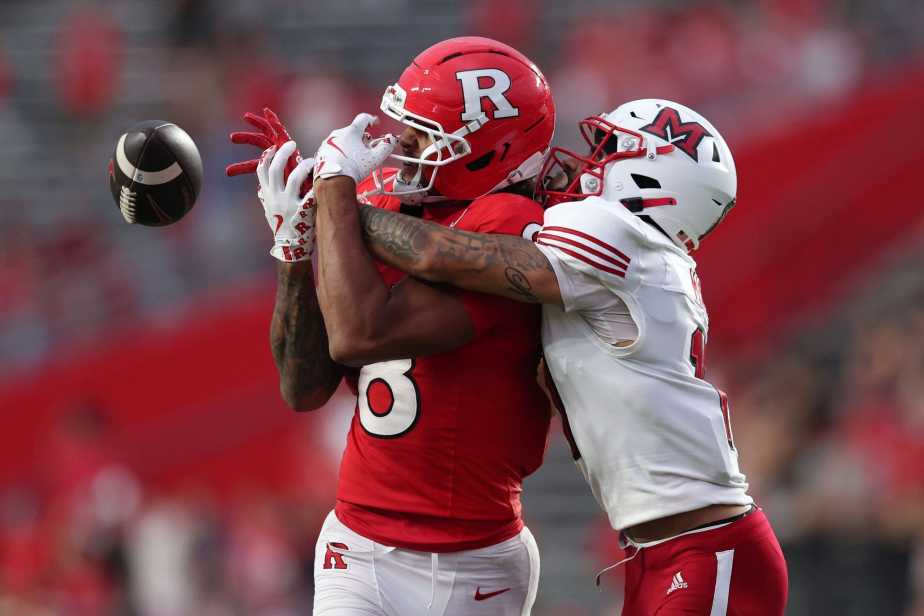 Rutgers wide receiver KJ Duff in red jersey (#8) battles for a contested catch with Miami (Ohio) defensive back in white jersey