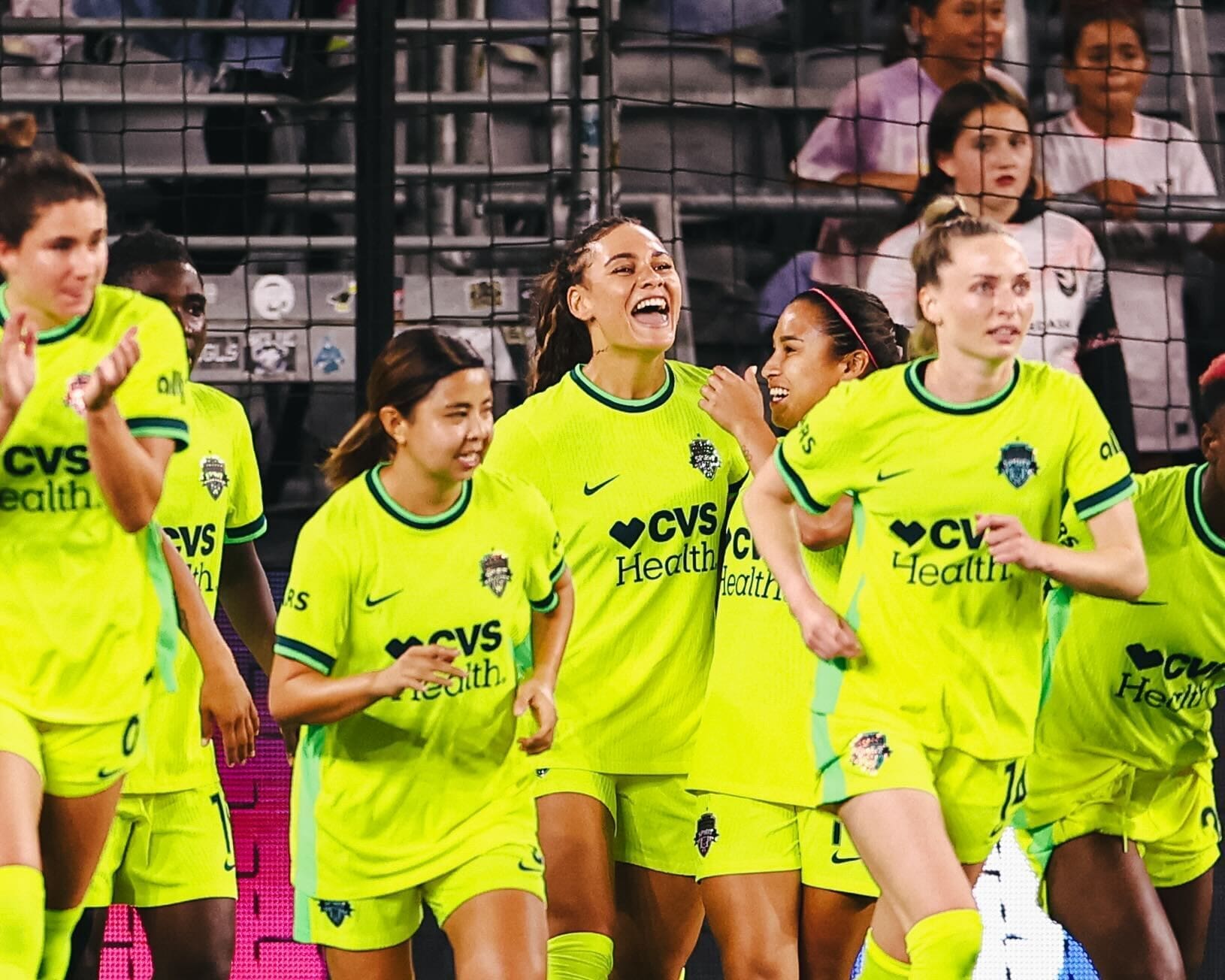 Washington Spirit players in bright yellow CVS Health jerseys are celebrating after Trinity Rodman's penalty goal, team united in a joyful moment