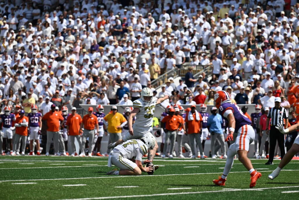 Georgia Tech kicker Aidan Birr follows through on his historic 55-yard game-winning field goal attempt as time expires, with teammates and coaches celebrating in the background at Bobby Dodd Stadium
