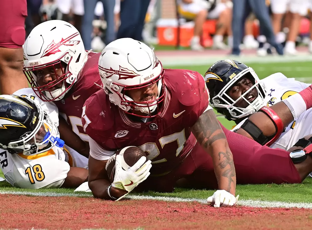 Florida State running back Gavin Sawchuk (#27) in white uniform crosses the goal line into the end zone for a touchdown during game action
