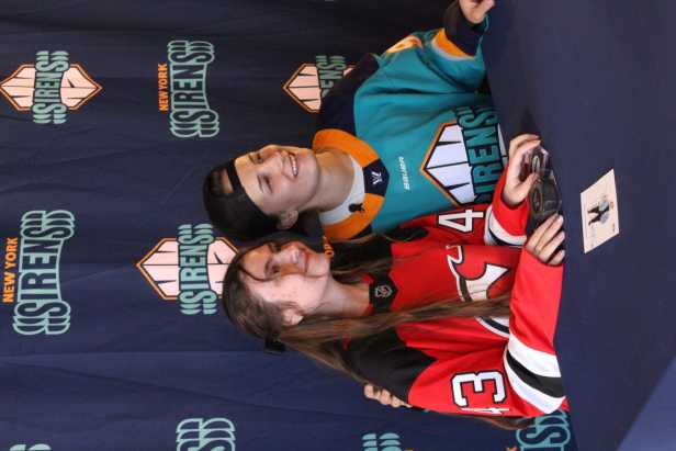 Young female hockey fan in New Jersey Devils Luke Hughes jersey posing with New York Sirens draft pick Kristyna Kaltounkova