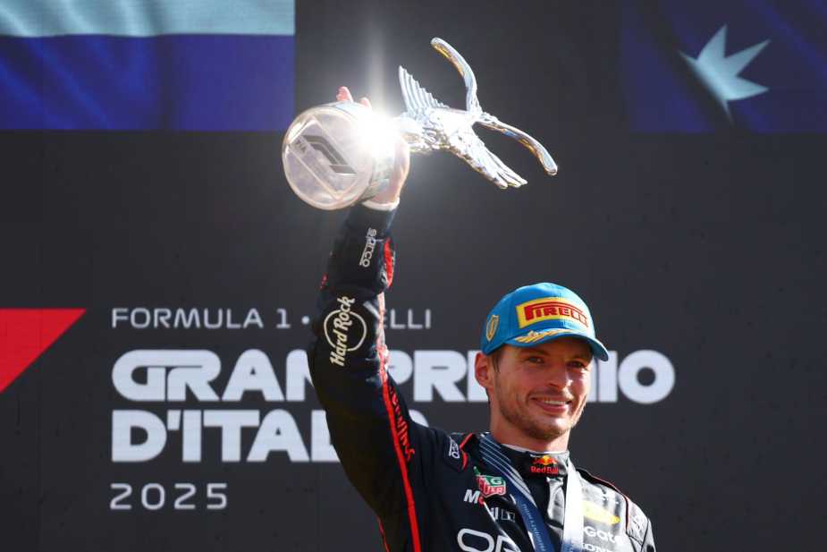 Max Verstappen raises the Italian Grand Prix winner's trophy above his head on the Monza podium after his record-breaking victory