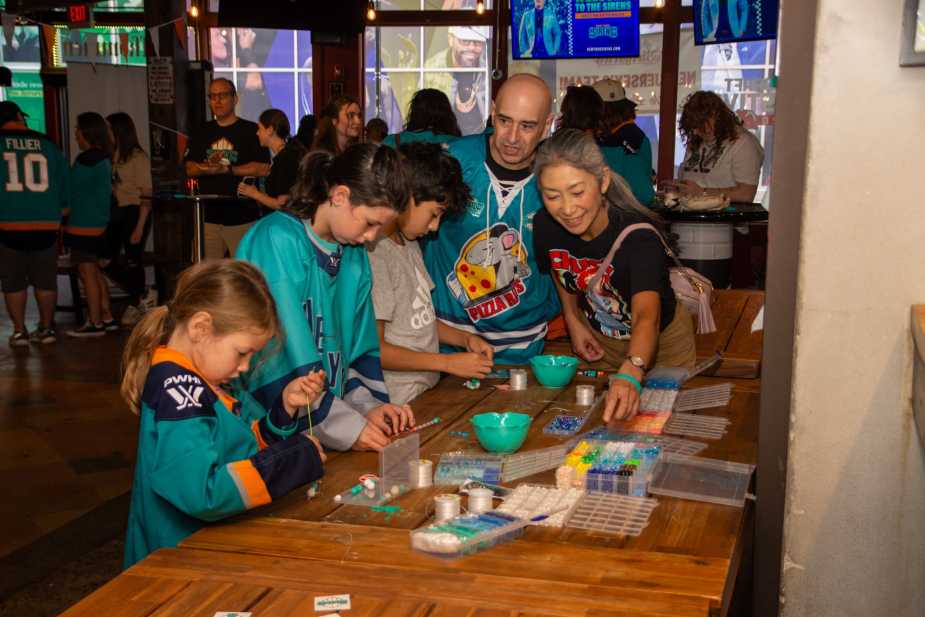 New York Sirens fans including Pizza Rat family making friendship bracelets at craft table during meet and greet