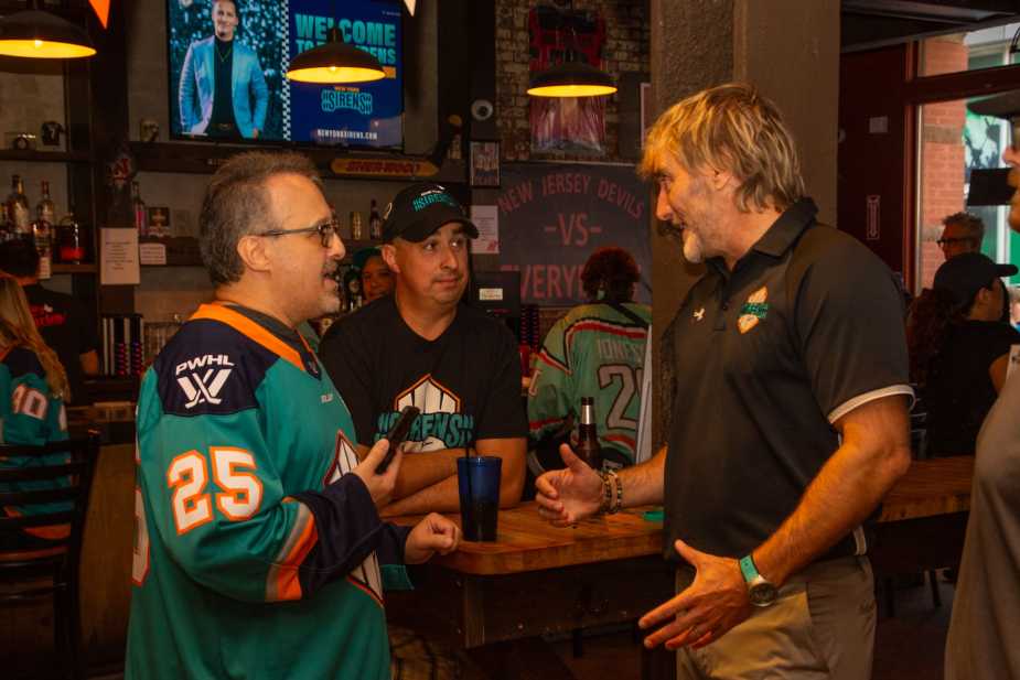 New York Sirens GM Pascal Daoust speaking with two male fans at venue bar