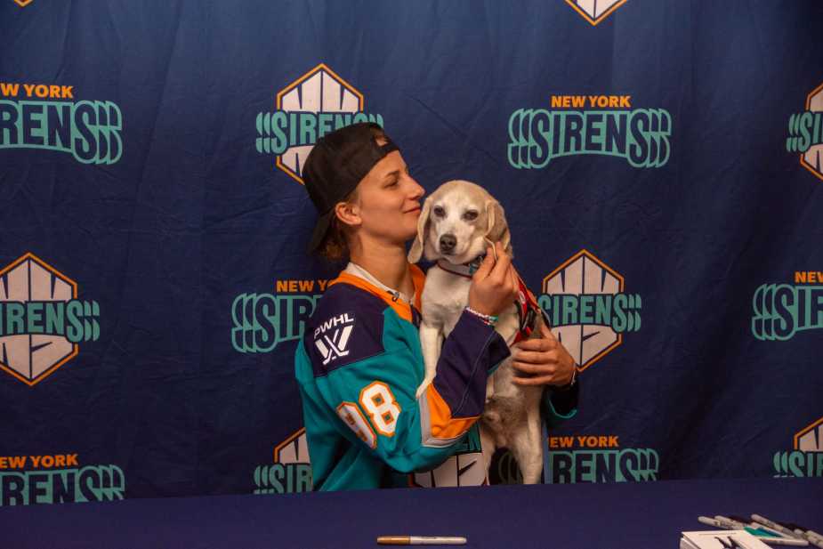New York Sirens draft pick Kristyna Kaltounkova holding and posing with a small dog at signing table