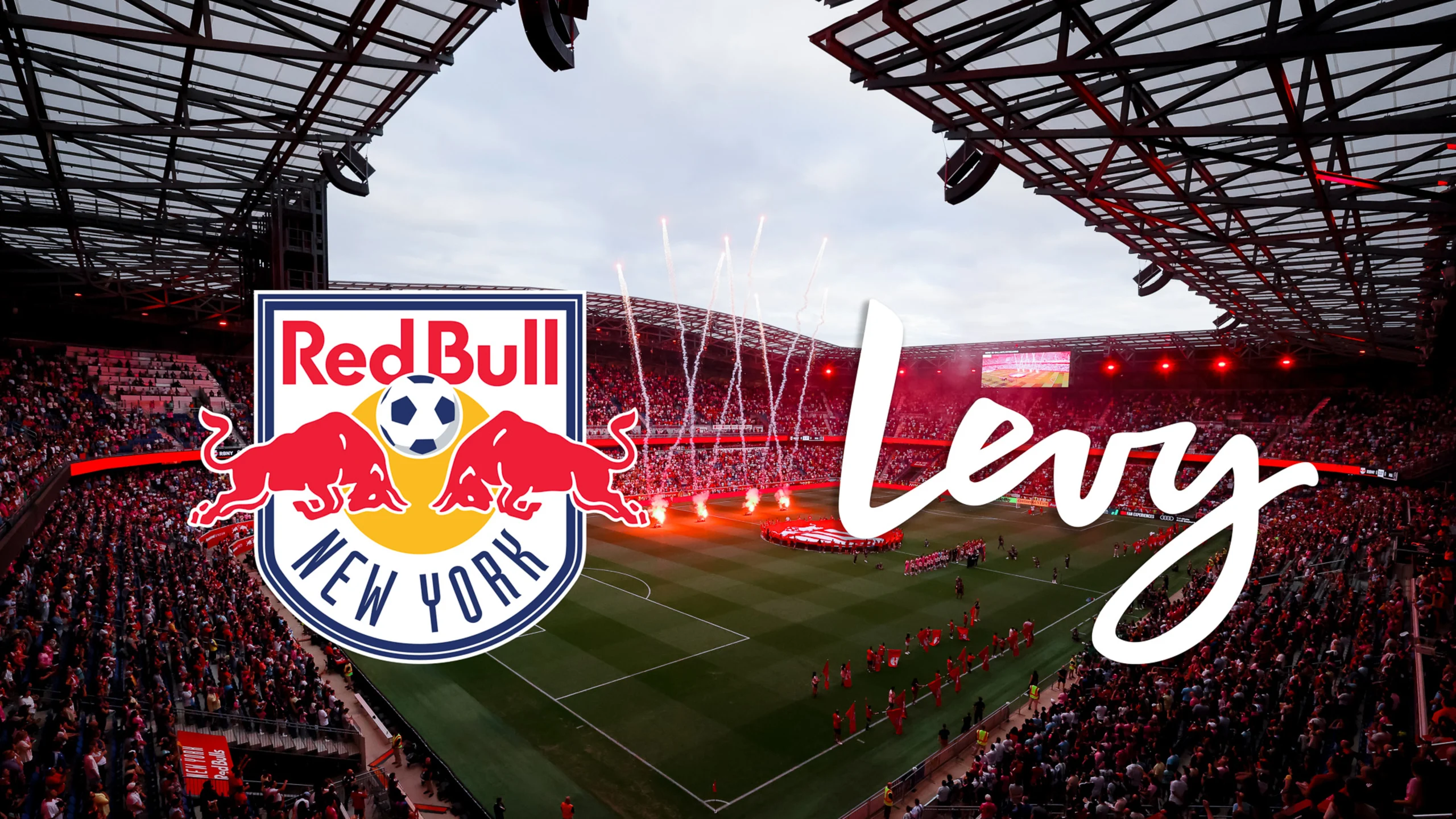 New York Red Bulls players celebrating together on the field, wearing red and white jerseys, showing team unity and excitement