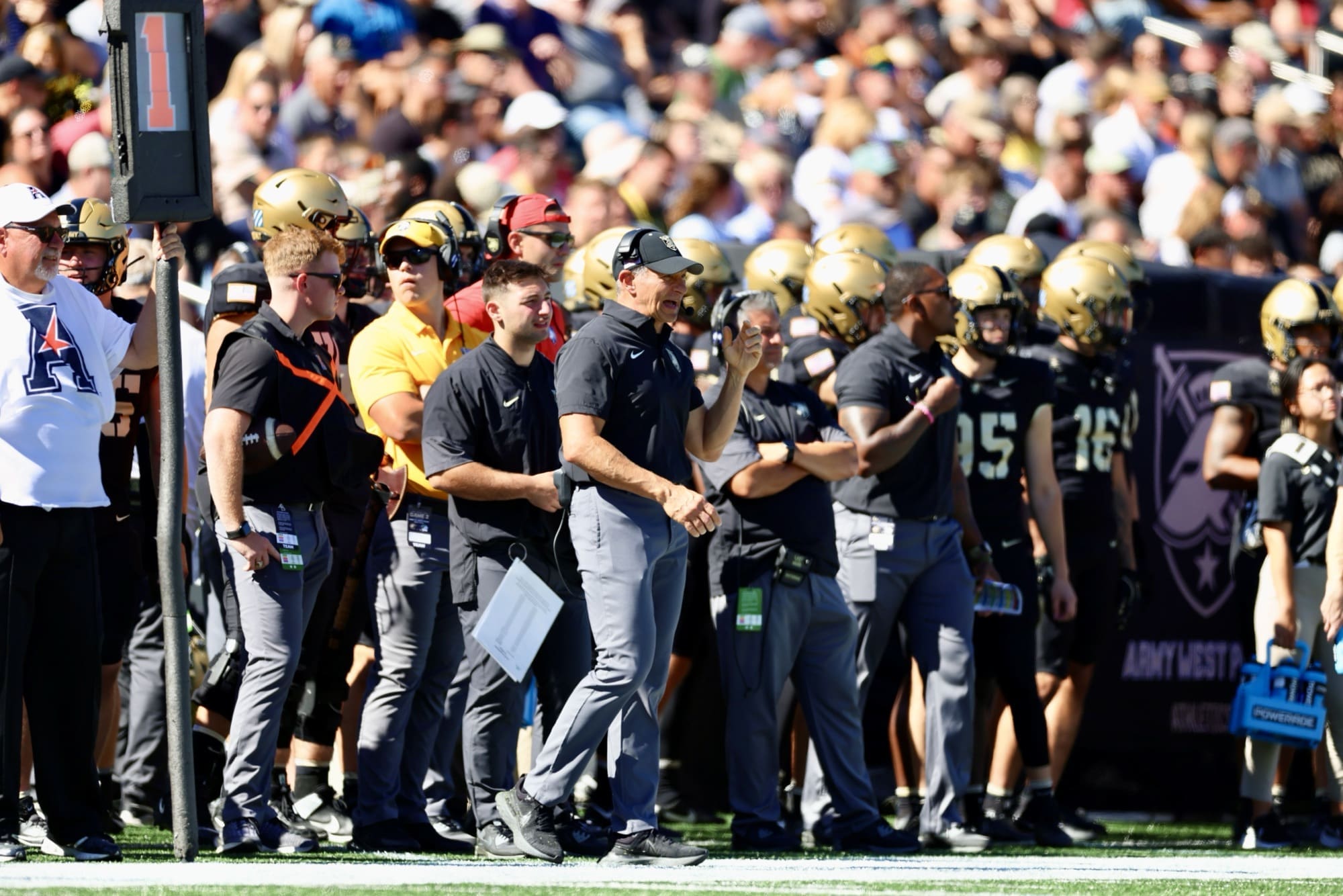 Army Black Knights Head Coach Jeff Monken stands on the sideline during the North Texas game at Michie Stadium, surrounded by coaching staff and players in Army's gold helmets
