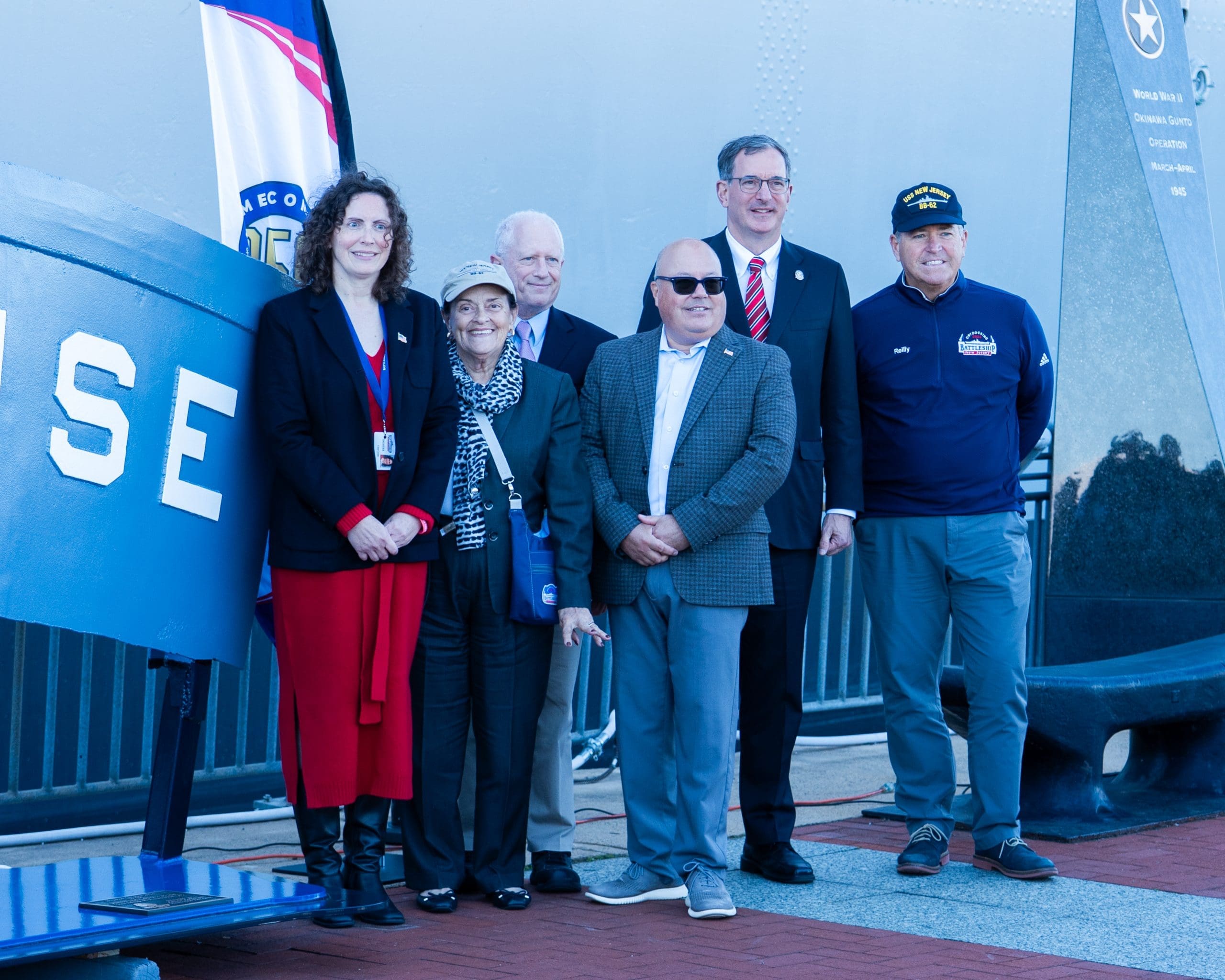 George Leon and Mayor Mark Bromberg pose with World War II veterans and family members beside the USS Enterprise stern plate at Battleship New Jersey in Camden, NJ, during the Navy 250th anniversary celebration on October 10, 2025.