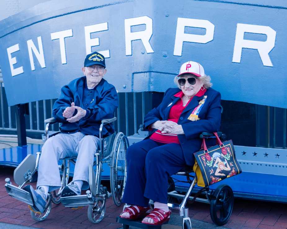 Paul Robbins, 100-year-old World War II veteran, and Rose Jordan, 102-year-old original Rosie the Riveter, pose beside the USS Enterprise stern plate at Battleship New Jersey during Navy 250th anniversary celebration on October 10, 2025.