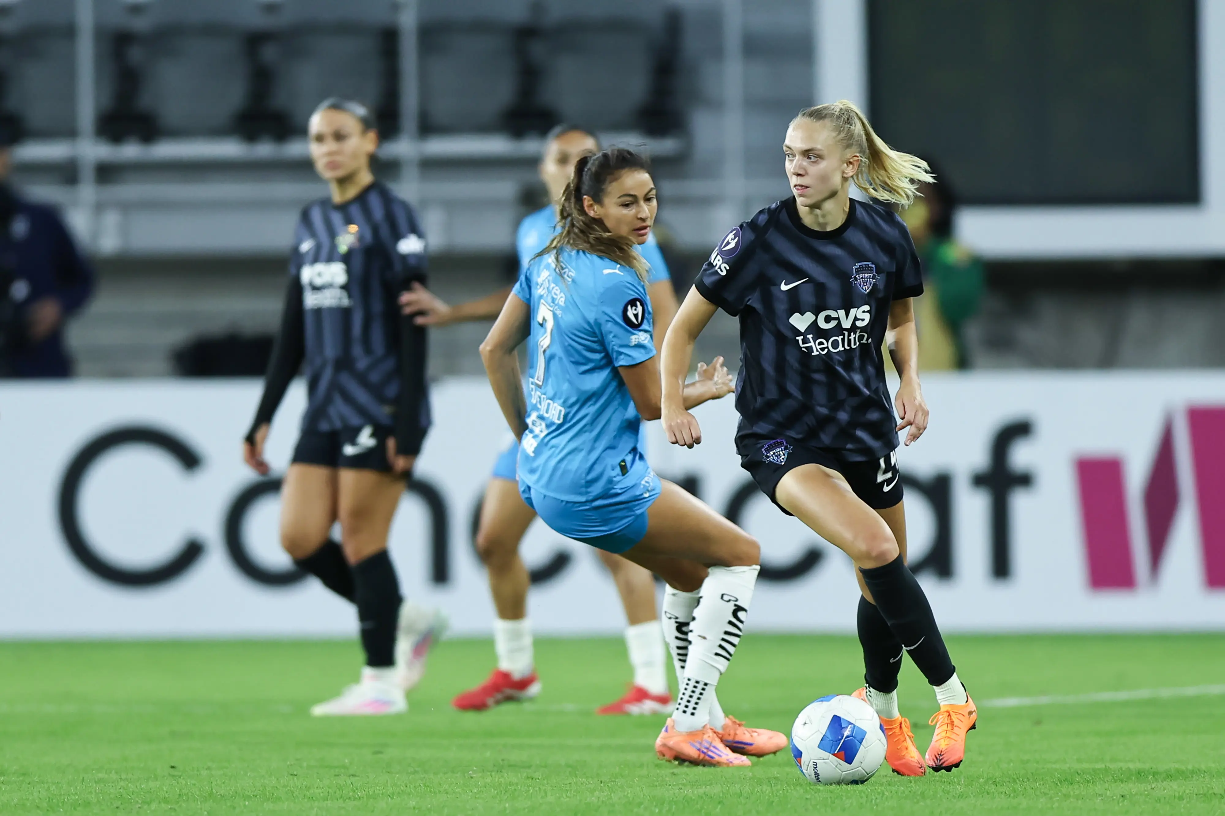 Washington Spirit defender Esme Morgan controls the ball while advancing past Monterrey Femenil midfielder Tanna Sánchez during the Concacaf W Champions Cup Group Stage match, with Trinity Rodman supporting in the background.
