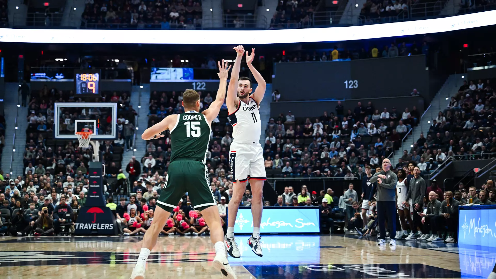 UConn Huskies forward Alex Karaban number 11 shoots a three-pointer over Michigan State Spartans center Carson Cooper number 15 during exhibition game at PeoplesBank Arena in Hartford Connecticut