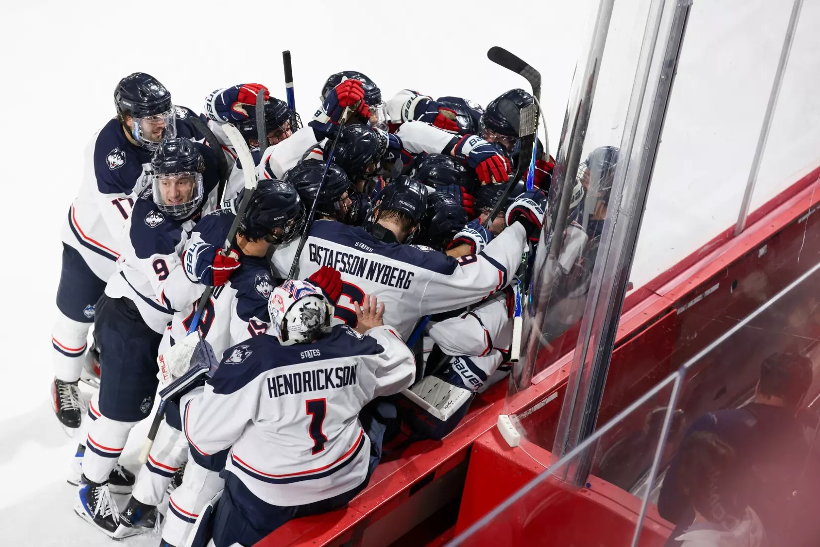 UConn Huskies men's ice hockey team celebrates together on ice after upset victory over No. 11 Northeastern