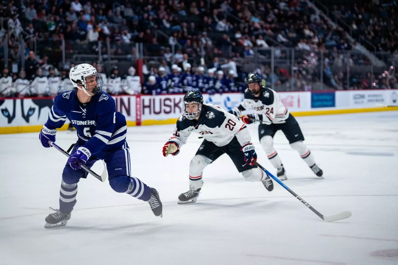 Stonehill's Ryan Davis races down the ice on a breakaway, pursued by UConn forwards Kaden Shahan and Carlin Dezainde during the Huskies' 3-3 overtime tie against the Skyhawks at PeoplesBank Arena on November 25, 2025.