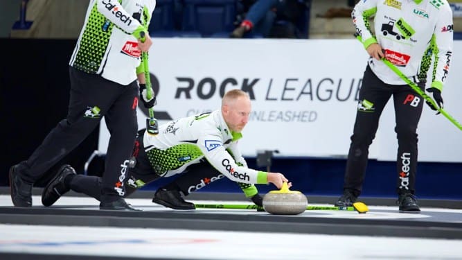 Rock League curlers deliver a stone with sweepers ready during live gameplay on a branded sheet.