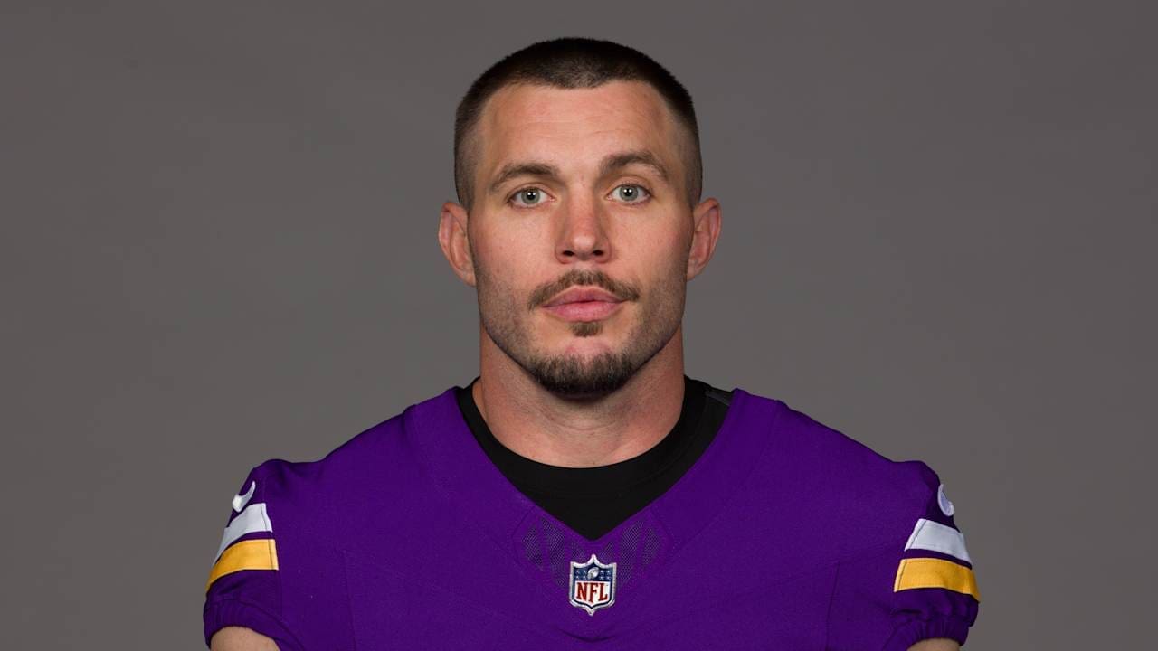 Minnesota Vikings player in purple jersey poses for official team portrait against a gray background.