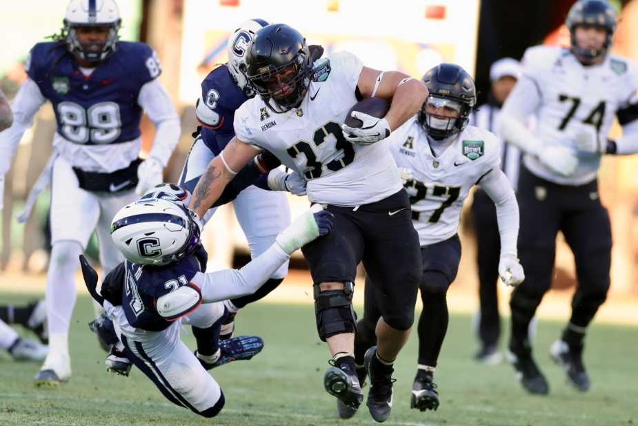 12/27/25, Boston, Massachusetts , Fenway, (#33) Jake Rendina of the Army Black Knights stiff-arms a UConn defender while rushing up the middle for a 15-yard gain during the first half of the Wasabi Fenway Bowl. Mandatory Credit: Jose Pichirilo / Bad Dawg Sports