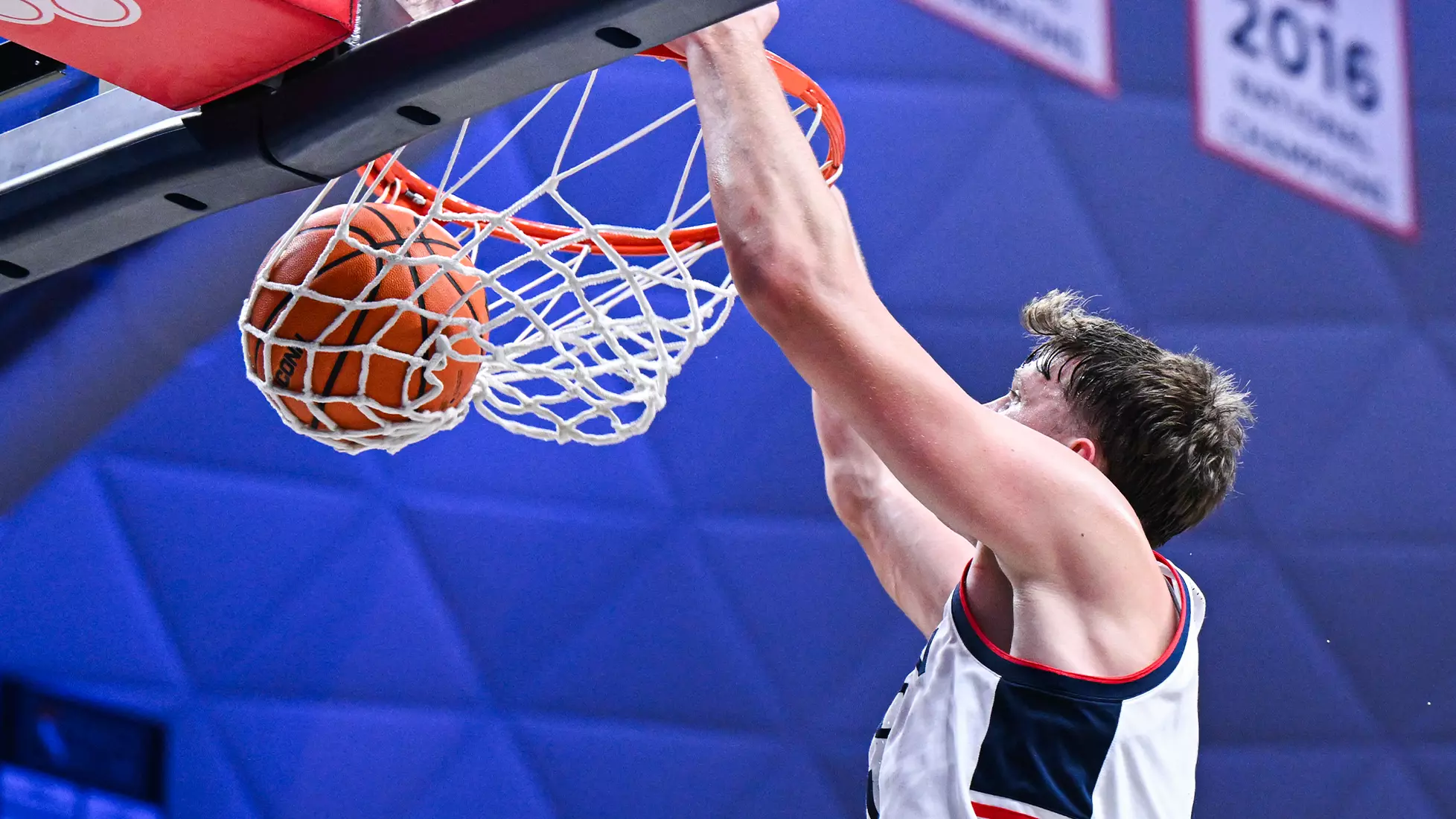 UConn Huskies player dunks basketball during home game at Gampel Pavilion