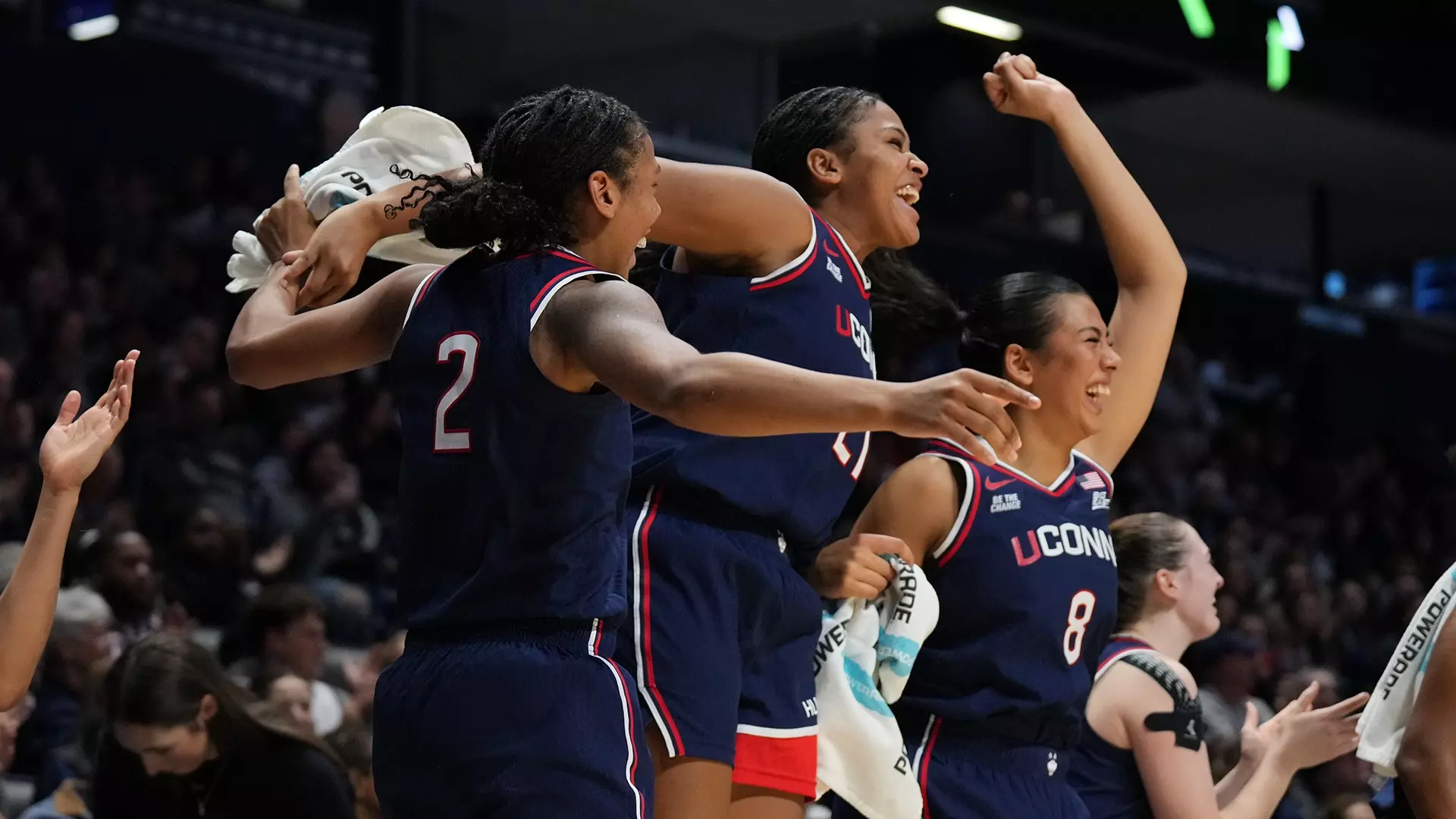 UConn Huskies women's basketball bench players celebrate enthusiastically during their 104-39 blowout victory over Xavier at Cintas Center, jumping and cheering as teammates tie season-high with 18 three-pointers in Big East opener