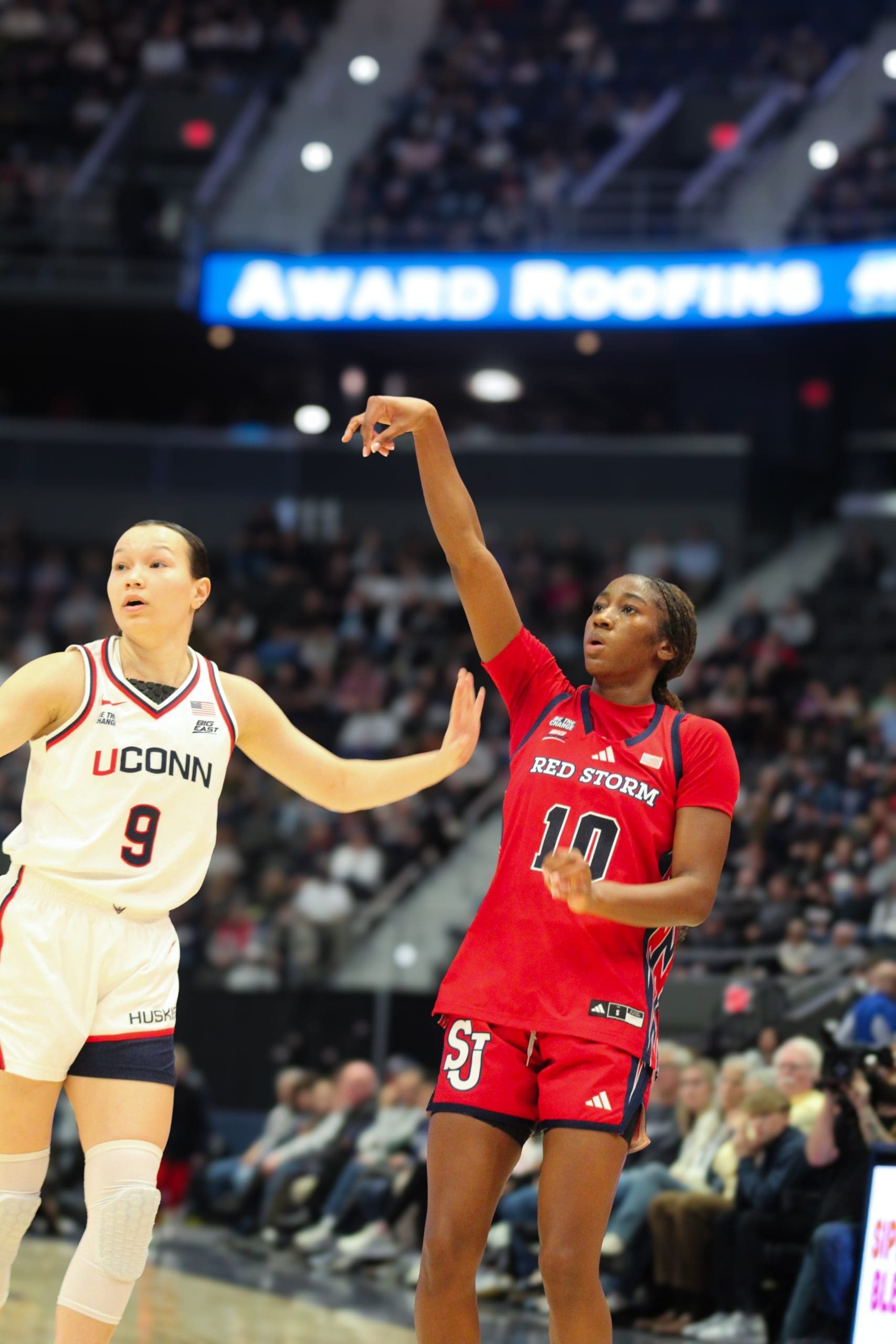 St. John’s Brooke Moore (#10) releases a jump shot over UConn’s Kayleigh Heckel (#9) during a women’s basketball game.