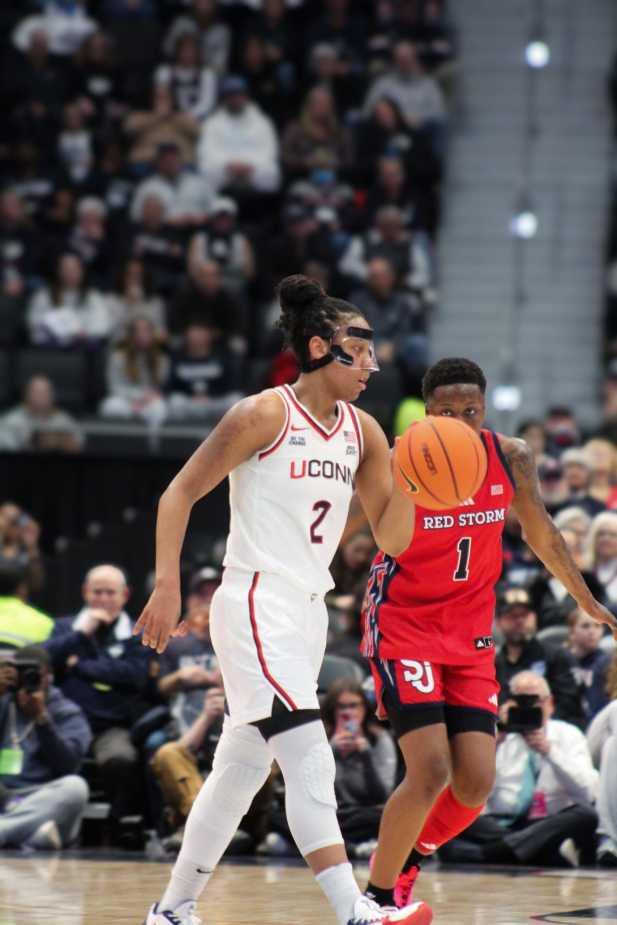 UConn’s KK Arnold (#2) defends as St. John’s guard (#1) dribbles upcourt during a women’s basketball game.
