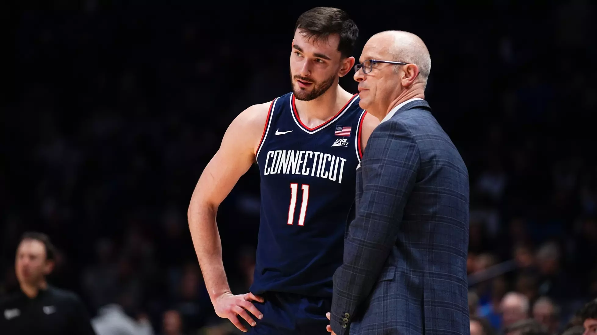 UConn men’s basketball player Alex Karaban (#11) listens to head coach Dan Hurley during a game, both focused on the court.