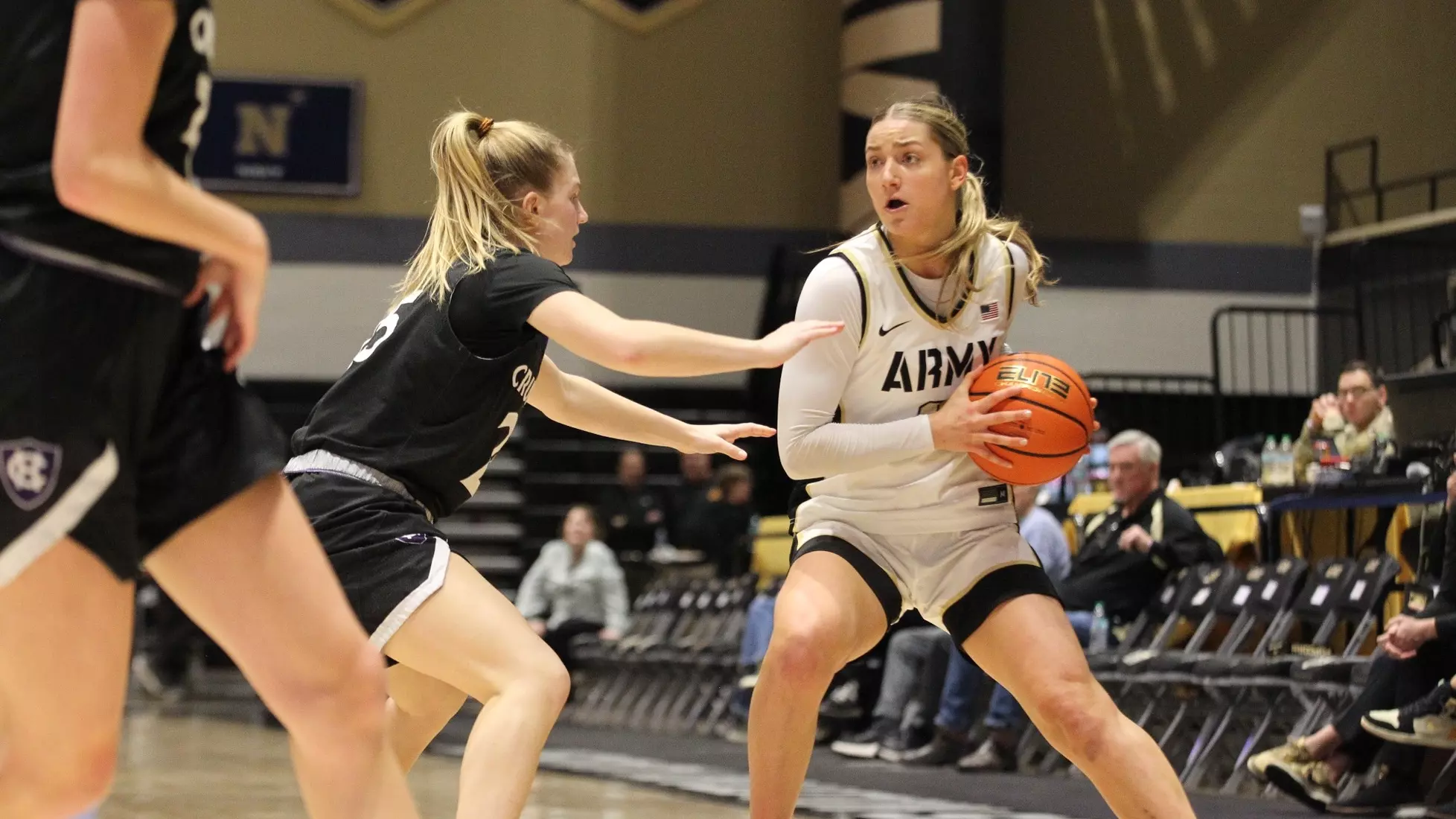 Army West Point guard Brooke Wilson holds the ball and surveys the floor on offense while defended by a Holy Cross player.