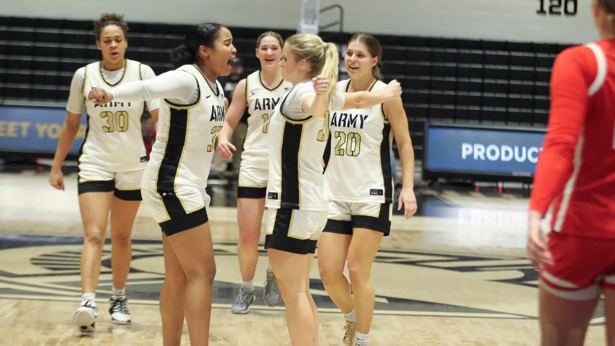 Army Black Knights women’s basketball players celebrate on the court with Reese Ericson after a clutch comeback win, all wearing white home uniforms. Mandatory Credit: Army Athletics