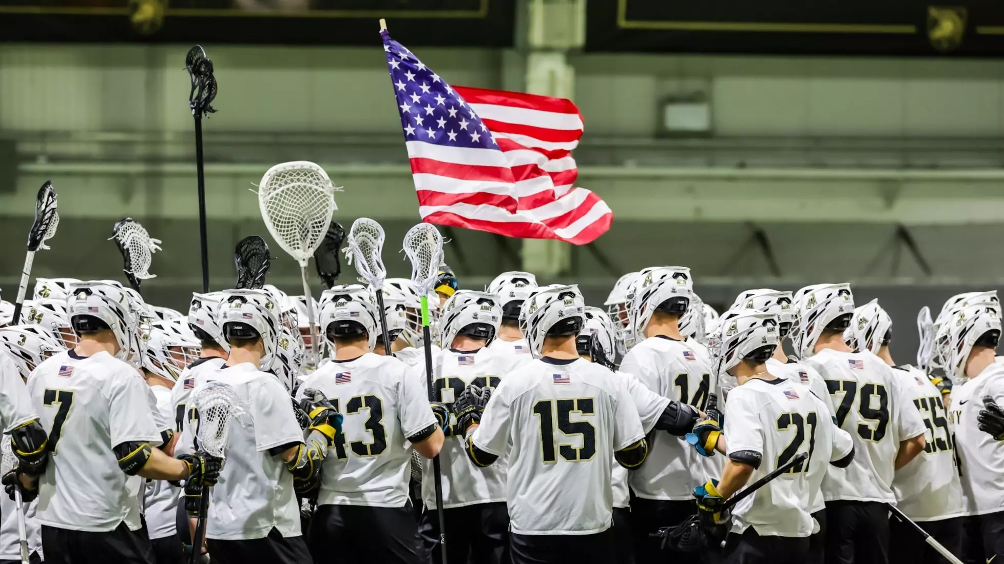 Army men’s lacrosse players gather at midfield with an American flag after their season-opening win at West Point.