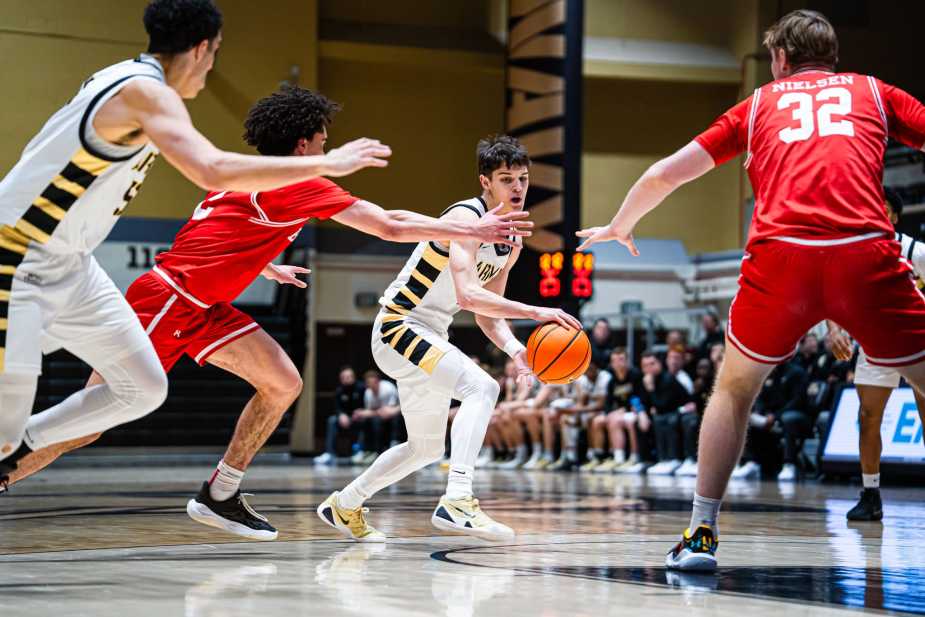 Army West Point freshman Jackson Furman dribbles into traffic and looks to deliver a bounce pass as Boston University defenders reach in at Christl Arena.