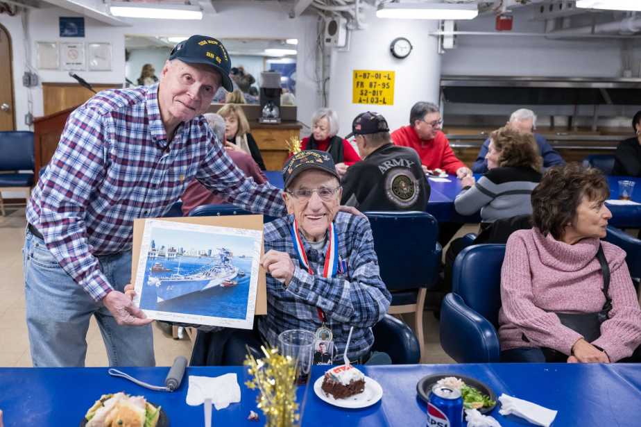 WWII Navy veteran John “Johnny Q” Quinesso Sr. smiles while posing with guests during his 100th birthday recognition ceremony aboard the Battleship New Jersey Museum in Camden, N.J.