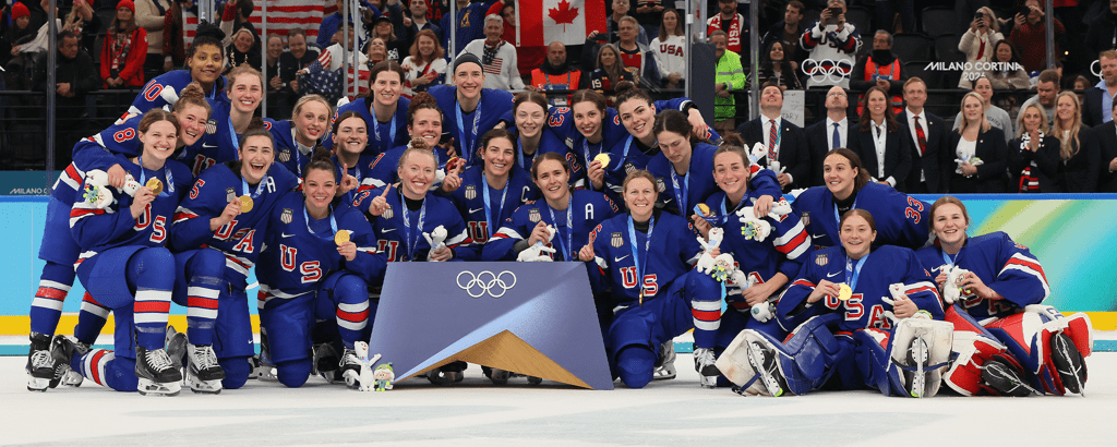 Team USA women’s hockey players pose for a team photo on the ice while holding up their gold medals after winning Olympic gold. Mandatory Credit: USA Hockey.