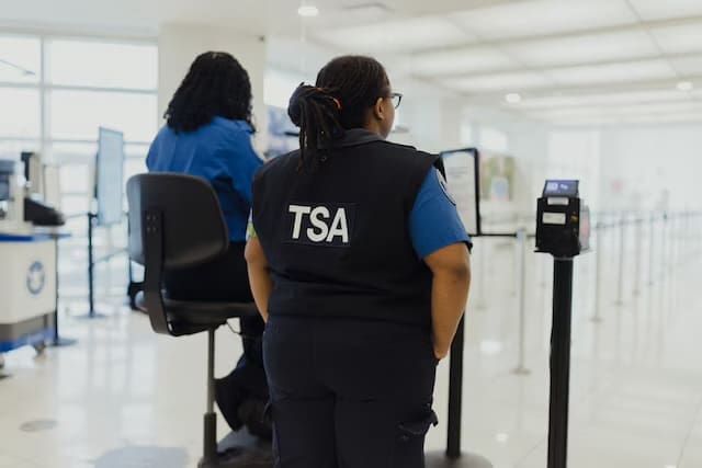 TSA agents work at a security screening checkpoint as passengers and carry-on items move through the inspection area.